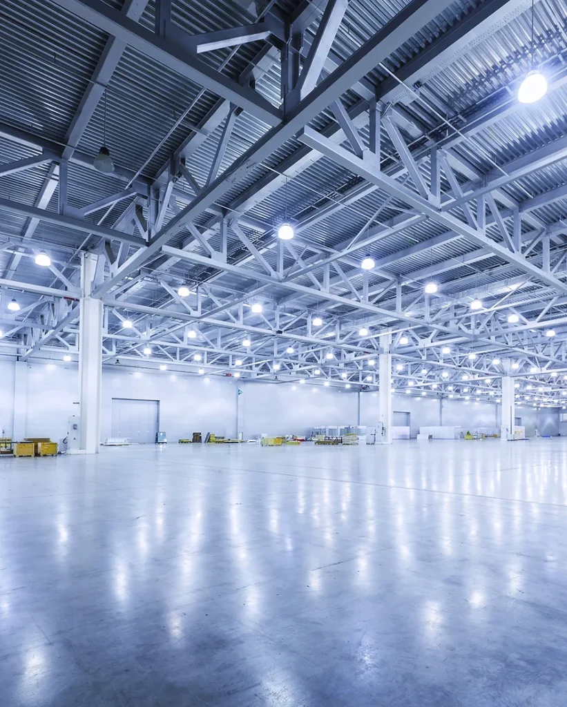 An empty warehouse illuminated by numerous lights, showcasing the work of an electrical engineering company