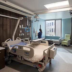 Hospital room with an empty bed and a nurse nearby, showcasing electrical engineering expertise in healthcare